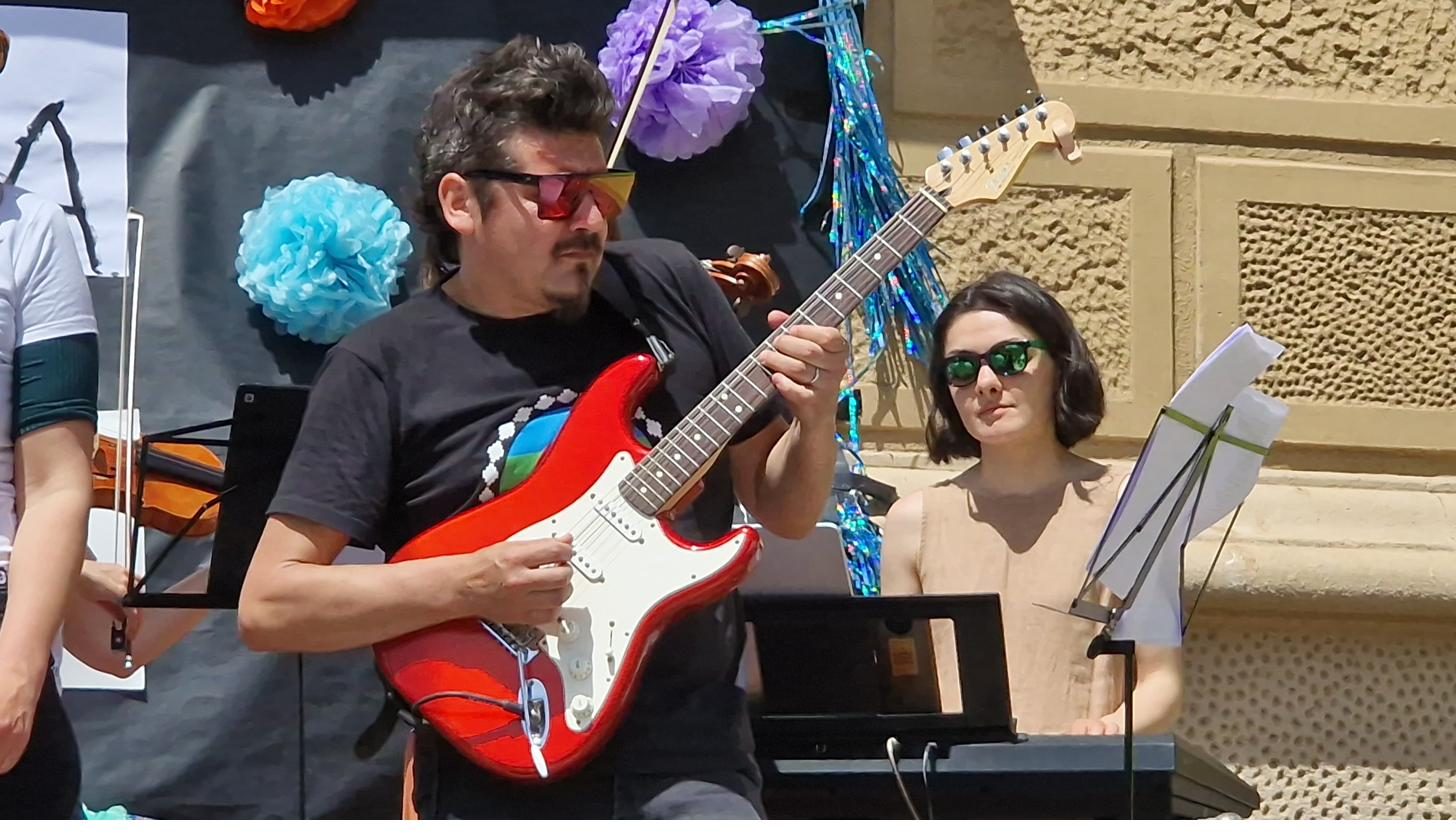 Un pare tocant la guitarra elèctrica vermella